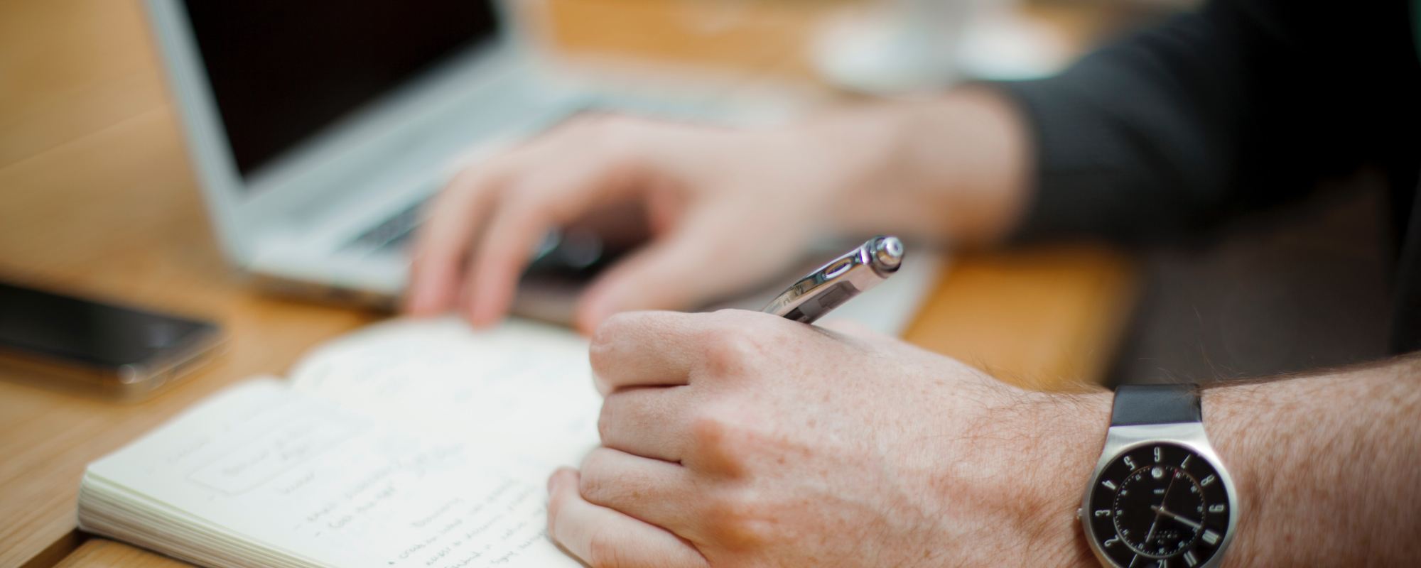man sitting while writing on notebook