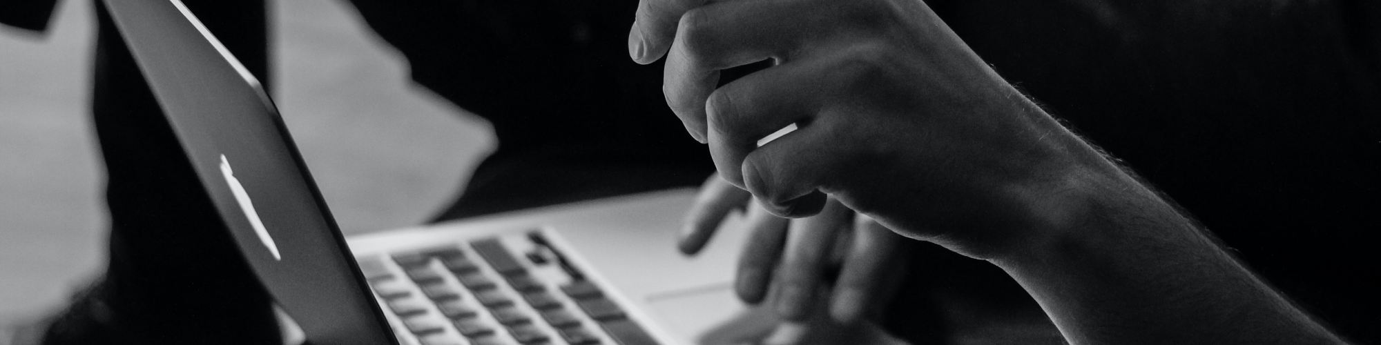grayscale photo of person using MacBook