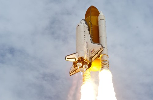 white and gold rocket launching toward blue sky
