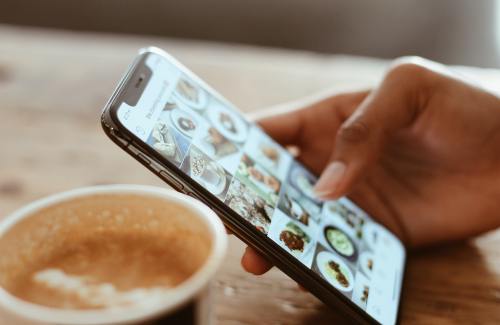 Person scrolling Instagram on a phone with coffee